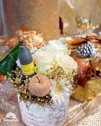 Composition florale du Nouvel An blanche et argentée avec rose blanche, pomme pailletée et mini champagne.